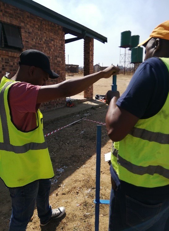 Two technicians in high-visibility vests working at a site
